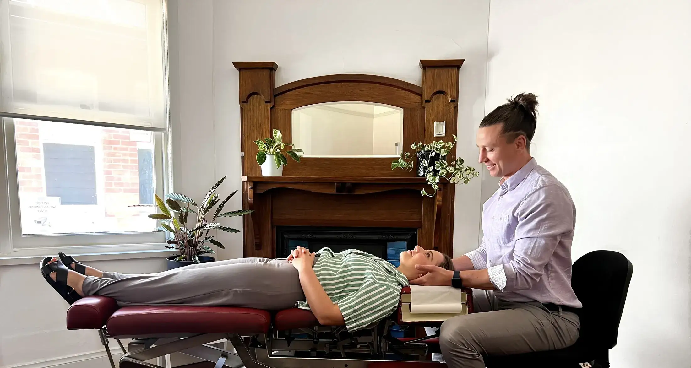 A chiropractor supporting a patient's neck with both hands on a treatment bench