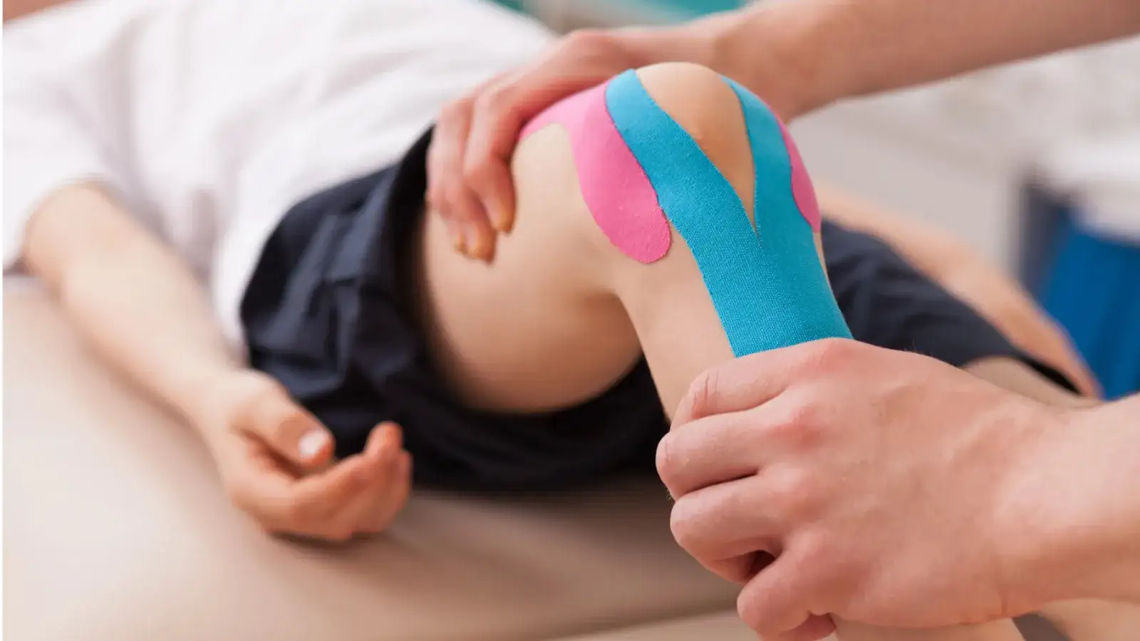 Kinesiology tape being applied over a patient's knee